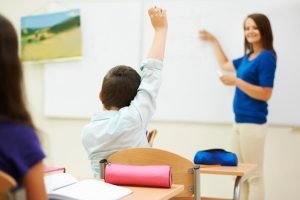 child raising up hand in classroom